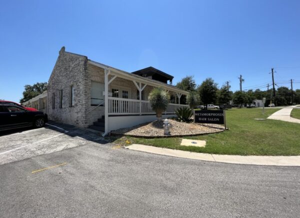 Exterior of the Metamorphosis Hair Salon, a stone building with a covered front porch in Austin